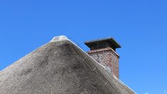 a tall brick chimney on top of a roof next to a building with a sky background