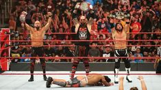 two men standing on top of a wrestling ring holding up their hands in the air