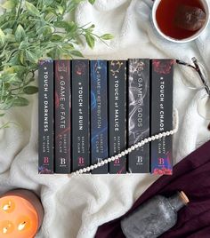 a table topped with books and candles next to a cup of tea on top of a blanket