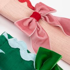 three different colored pieces of fabric with bows on them, one pink and one green