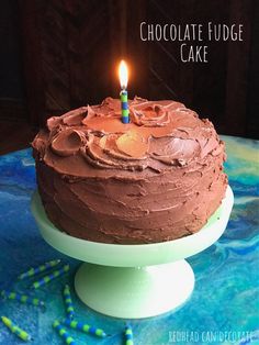 a chocolate fudge cake with a single lit candle on it's birthday cake