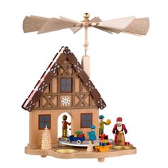 a toy house with windmills on top of it and toys in the foreground