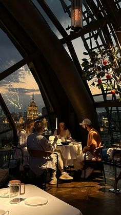 some people are sitting at a table in a restaurant with a view of the city