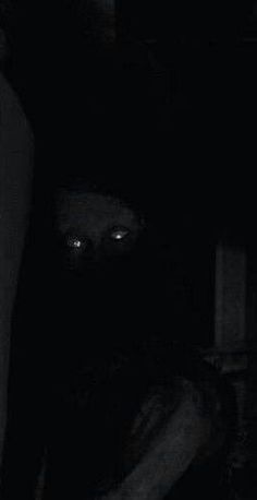 a person in the dark with their face obscured by a black mask and arm around him