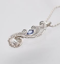 a silver necklace with a blue stone hanging from it's center, on a white background