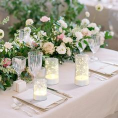 the table is set with candles, flowers and silverware for an elegant wedding reception