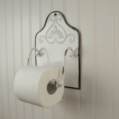 a white toilet paper holder hanging on a wall