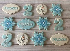 frosted cookies decorated with frozen characters and snowflakes are arranged on a wooden table