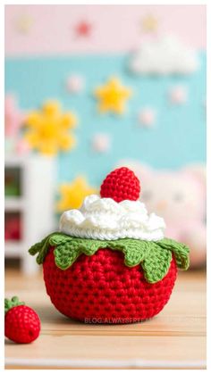 a crocheted strawberry bowl with whipped cream and strawberries on the top, sitting on a table