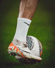 the legs and feet of a soccer player wearing white socks with orange accents on them