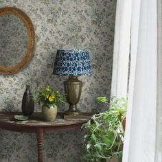 a table with two vases and a lamp on it in front of a window