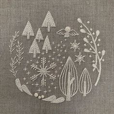 an embroidery pattern with trees and snowflakes in the center on a gray background