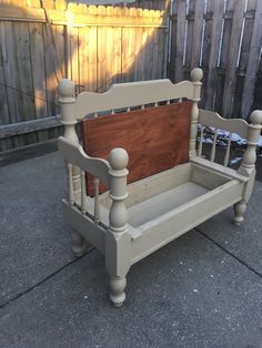 a wooden bench sitting on top of a cement ground next to a fence and yard