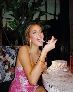 a woman sitting at a table with a cake in front of her and eating it