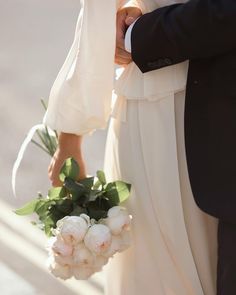 the bride and groom are holding bouquets of white flowers in their hands as they stand close to each other