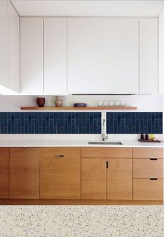 a kitchen with white cabinets and blue tile backsplashing on the counter top