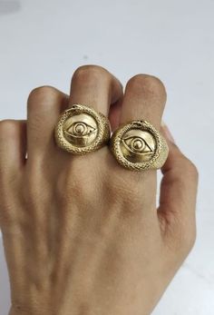 a person's hand with two gold rings in the shape of an all seeing eye