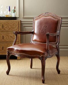 a brown leather chair sitting on top of a carpeted floor next to a dresser