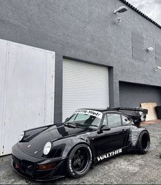 a black porsche parked in front of a garage