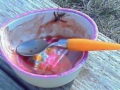 a cup with spoons in it sitting on top of a wooden table next to grass