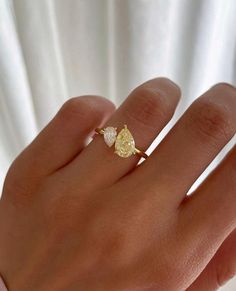 a woman's hand with a yellow diamond ring on top of her left hand