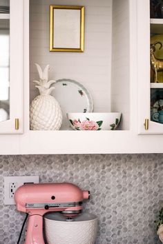 a pink mixer sitting on top of a counter next to a white bowl and pineapple