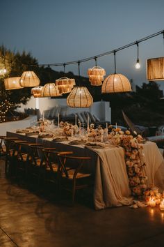 a long table is set up with candles and flowers for an outdoor wedding reception at night