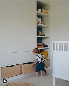 a little boy that is standing in front of some drawers