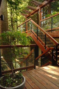 there is a wooden staircase going up to the top floor in this house with glass balconies