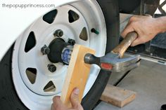 a man is working on a tire with a wrench and a piece of wood