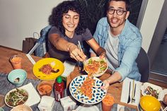 two people sitting at a table with plates of food