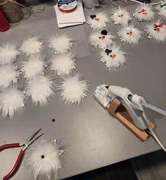 some scissors are laying on a table with white feathers and other items scattered around it