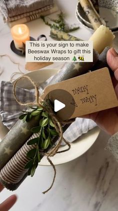 a person holding a wrapped gift in front of a table with candles and napkins