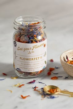 a jar filled with dried flowers next to a spoon