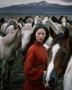 a woman standing in front of a herd of horses