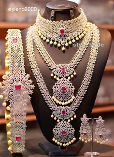 an elaborate necklace and earring set with red stones on display in front of a mannequin