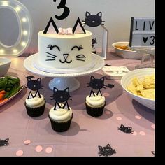 a cat themed birthday party with cupcakes, cake and other food on the table