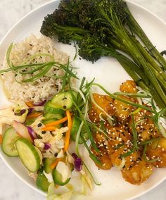 a white plate topped with meat and veggies next to rice covered in sesame seeds