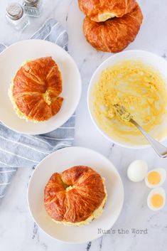 three white plates topped with croissants and eggs