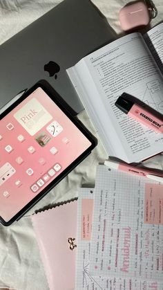 an ipad, notebook and pen sitting on top of a bed next to each other