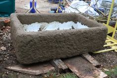 a concrete planter sitting on top of a pile of wood