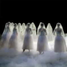 a group of women dressed in white veils standing in the clouds with their hands on their hips