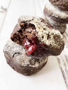 two chocolate cookies with cranberry filling and powdered sugar on top are stacked next to each other