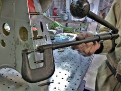 a man is working on an object in a factory with tools attached to the machine