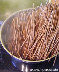 some sticks are in a metal bowl on the stove top, ready to be cooked