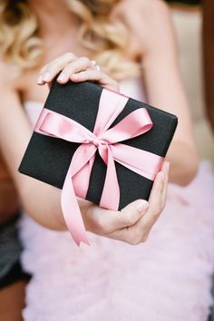 a woman holding a black and pink gift box