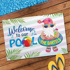 a welcome sign is sitting on the ground next to a pool with flip flops