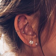 a woman's ear with three piercings on it