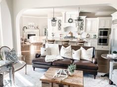 a living room filled with furniture next to a kitchen and dining room table in front of an archway