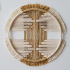 two pieces of woven art made from straw and other materials on a white table top